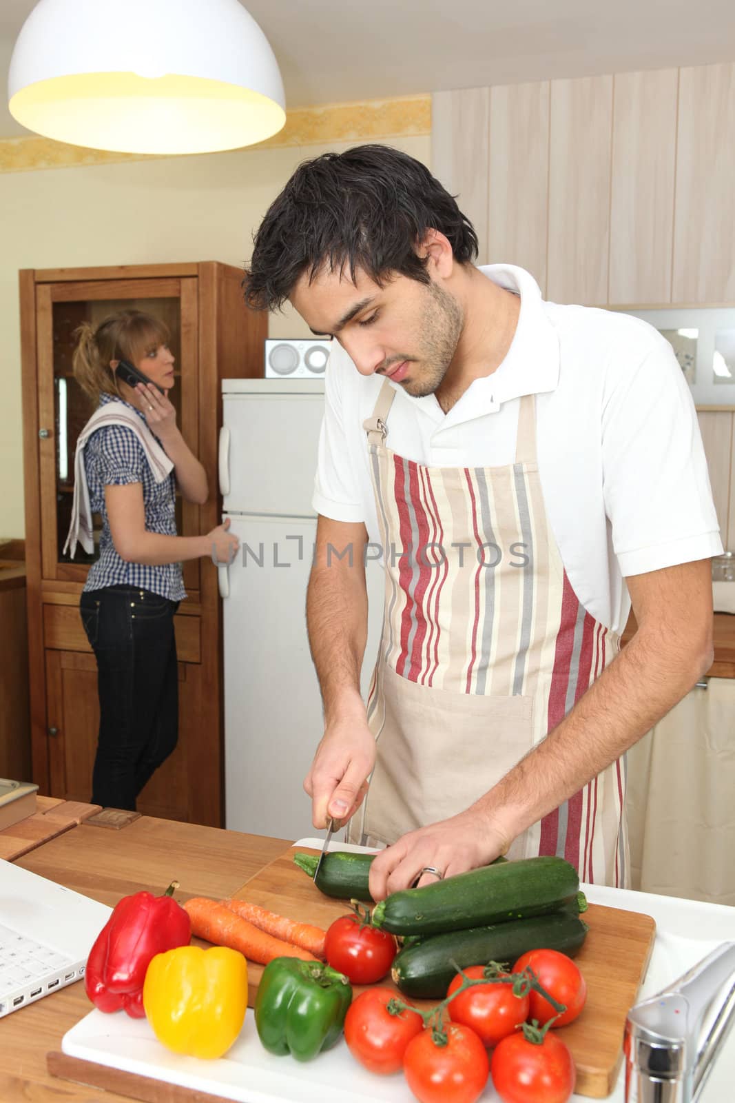 Woman on phone and man preparing meal by phovoir