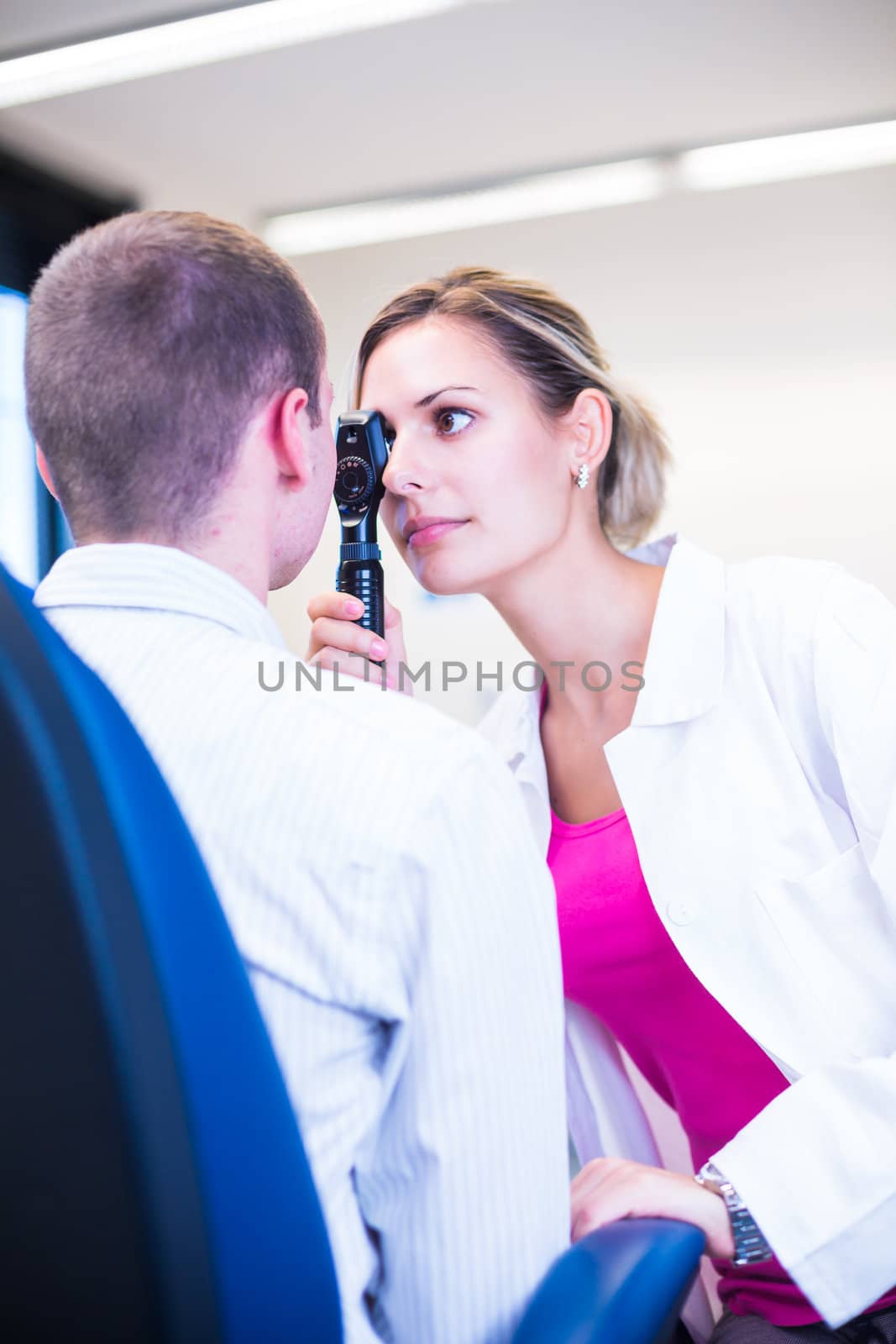 Optometry concept - handsome young man having his eyes examined by an eye doctor (color toned image; shallow DOF)