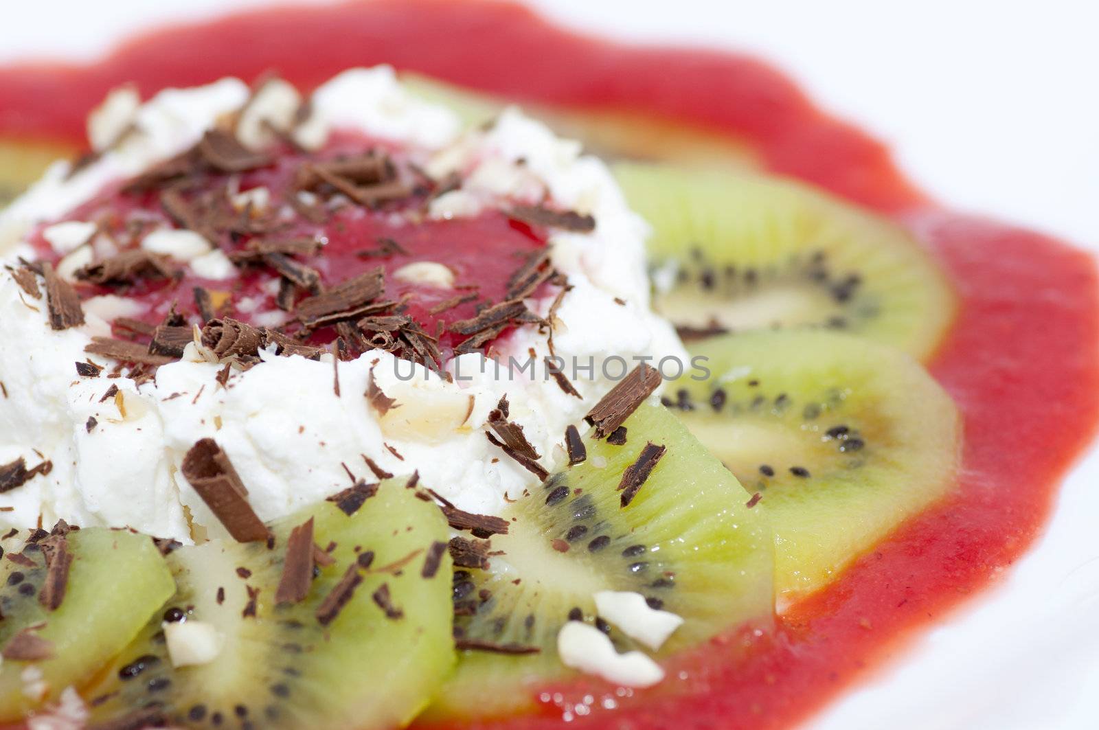 Dessert with cottage cheese served with chocolate shaving, grated nuts and sliced kiwi and strawberry jam