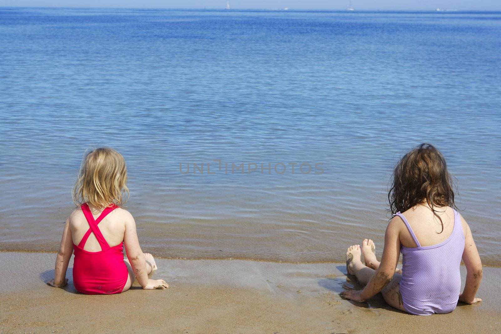 tow sisters sit on beach bathing suit swimsuit back view summer vacation