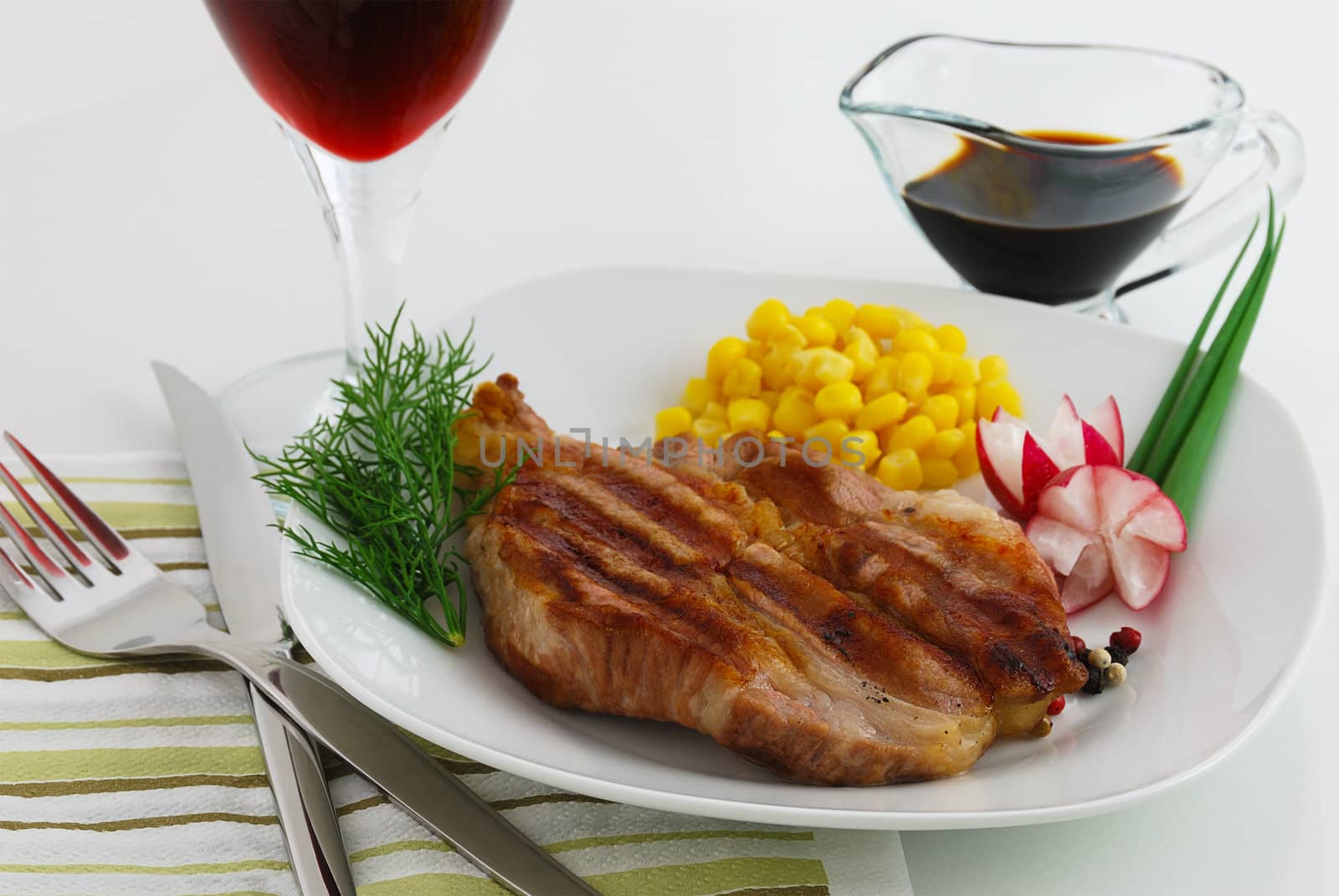 Steak dish garnished by corn, radish and dill served with wine and sauce