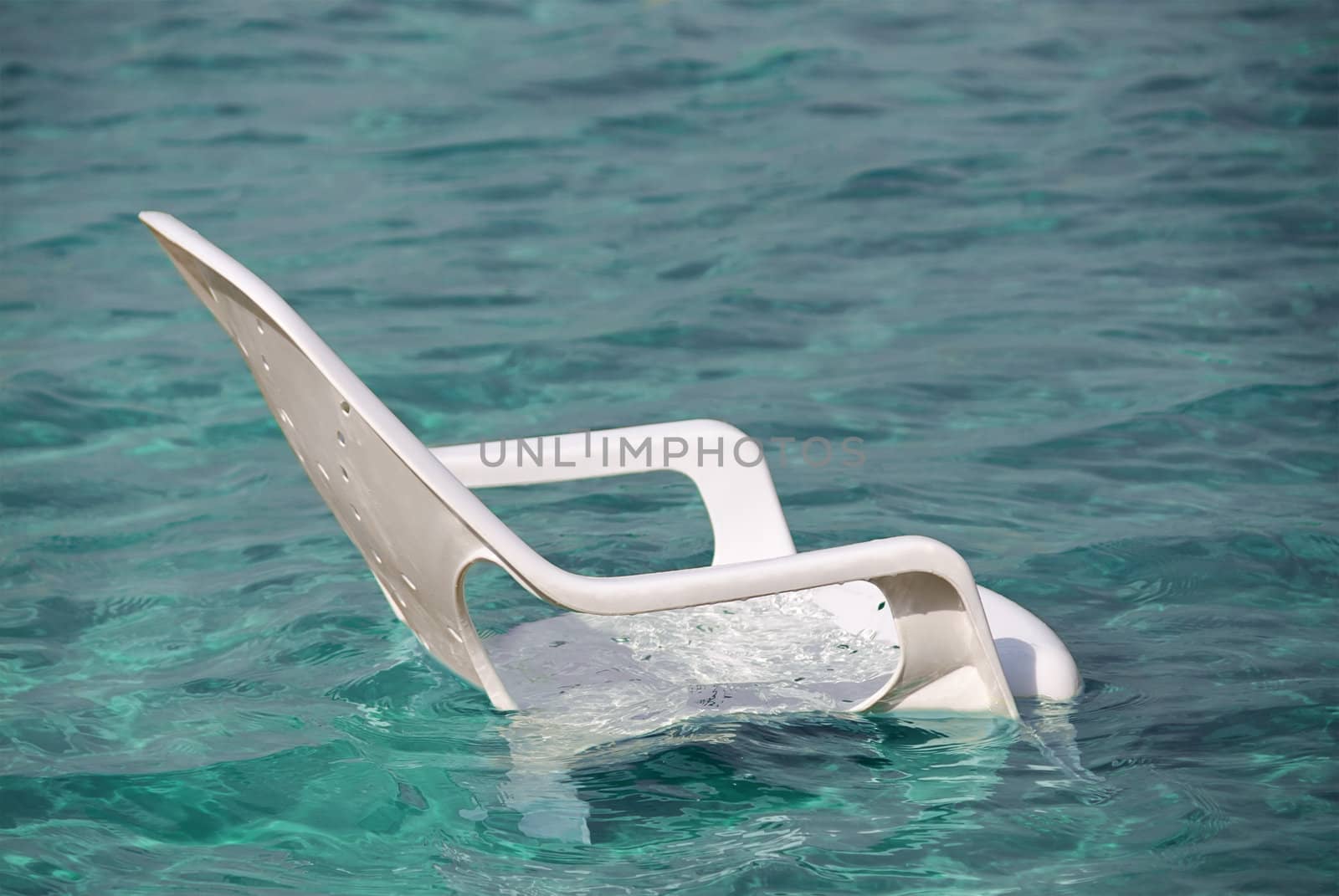 White plastic beach chair in clean blue water