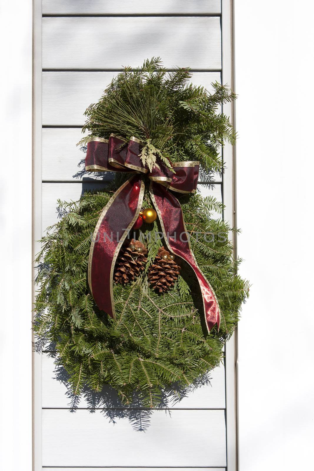 Christmas wreath hangs on the siding of a house.
