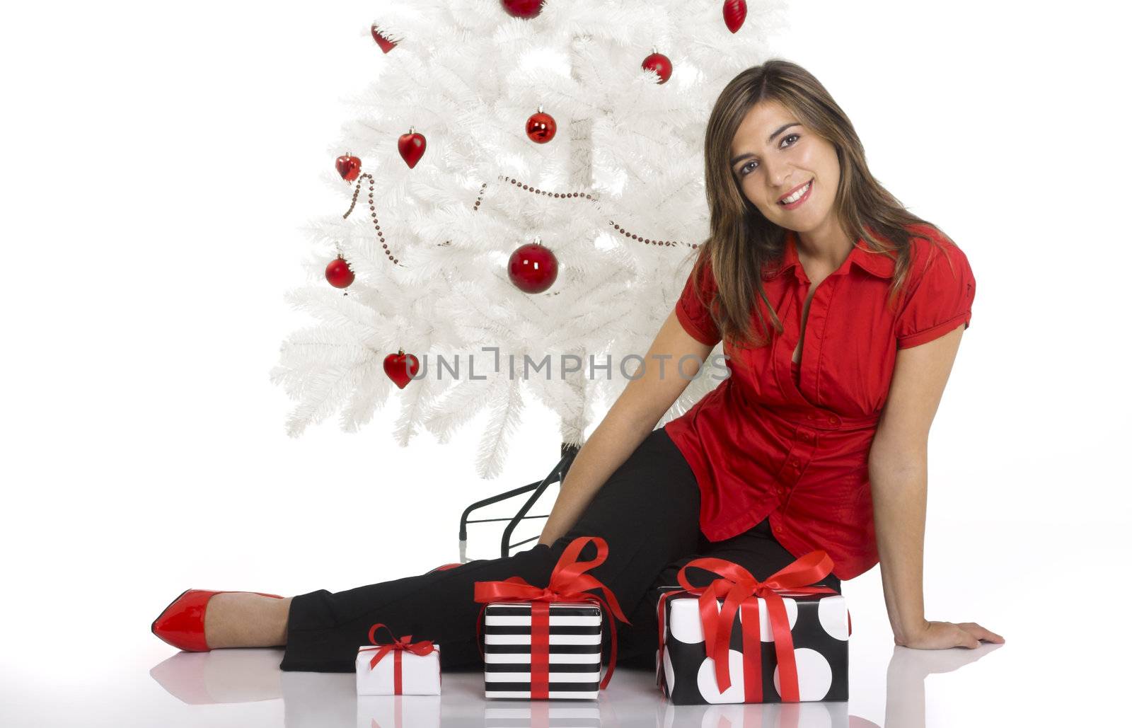 Beautiful happy woman near a white Christmas tree holding Christmas presents