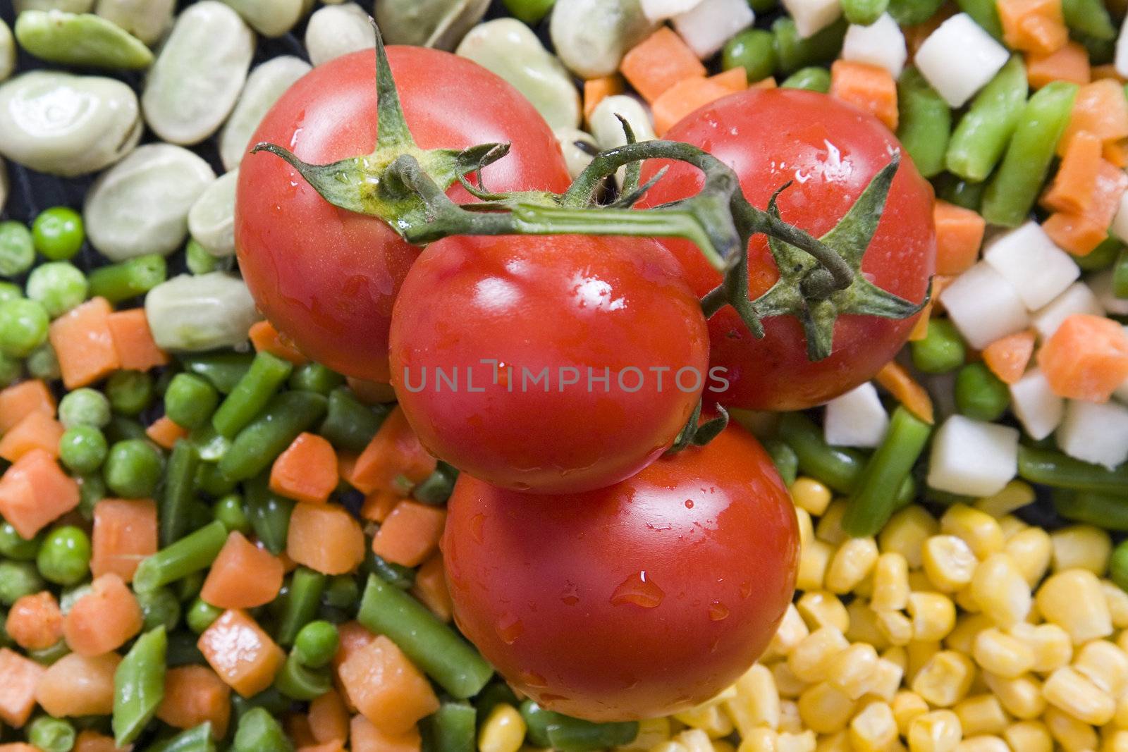 Fresh tomato on top of vegetables, corn, green beans 