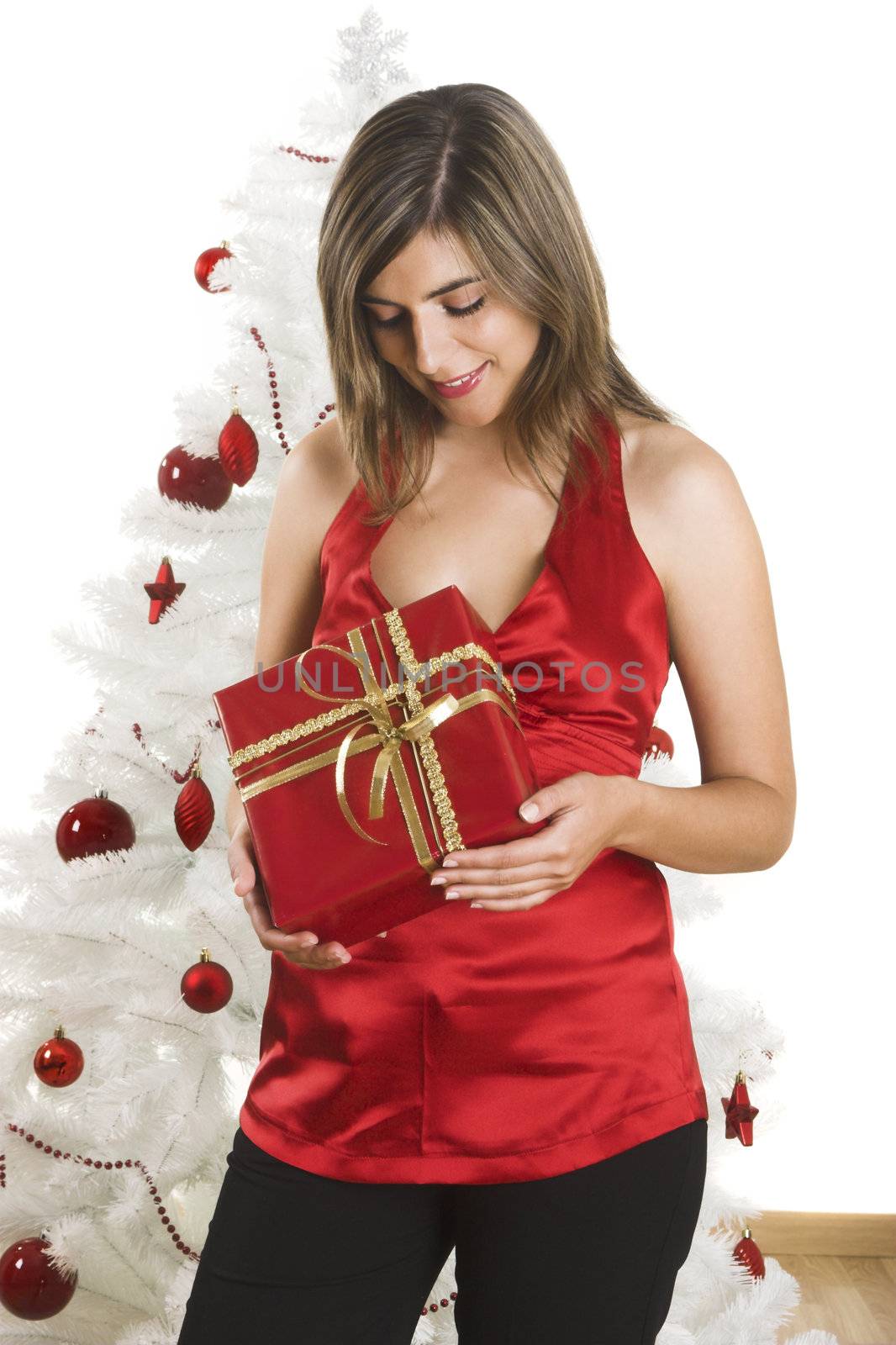 Beautiful happy woman near a white Christmas tree holding Christmas presents