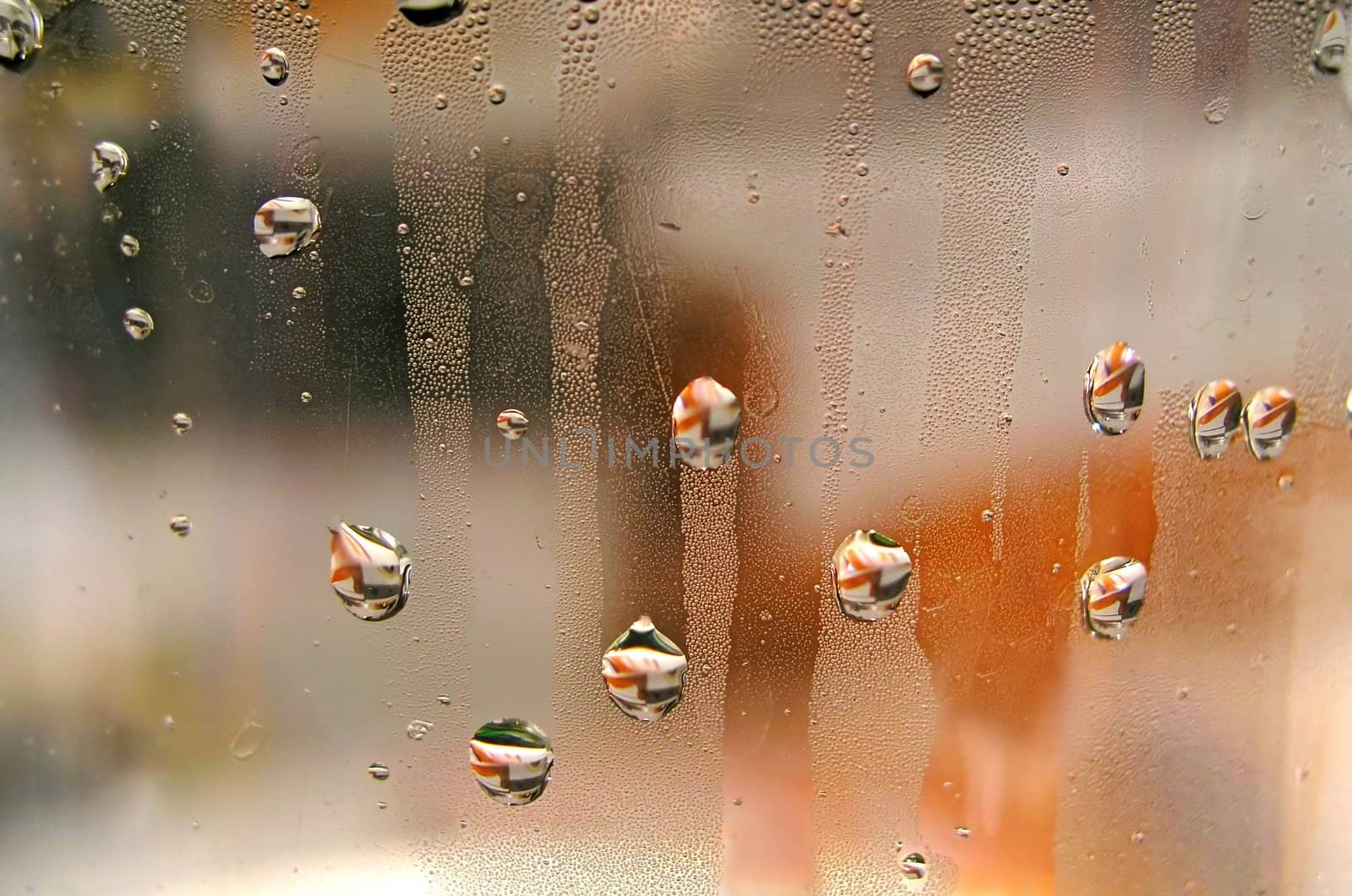 Droplets with colored reflections on a wet transparent surface 