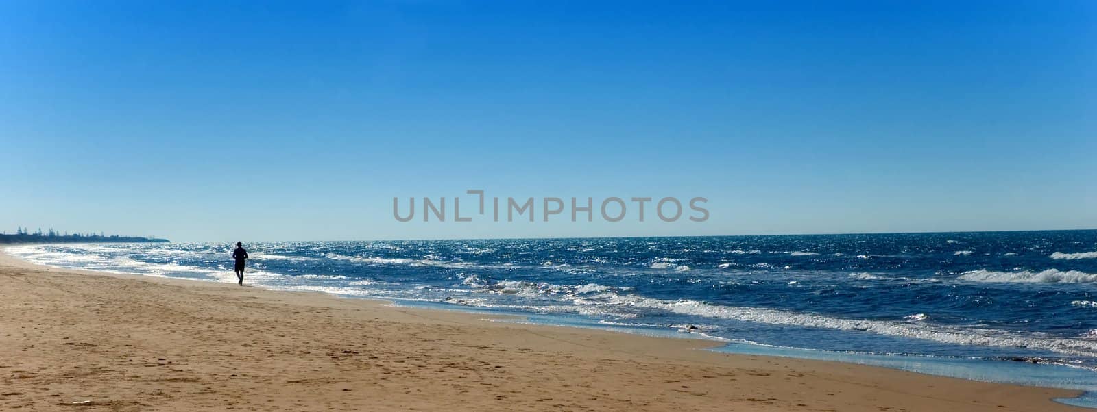 Beach with running man in the early morning light