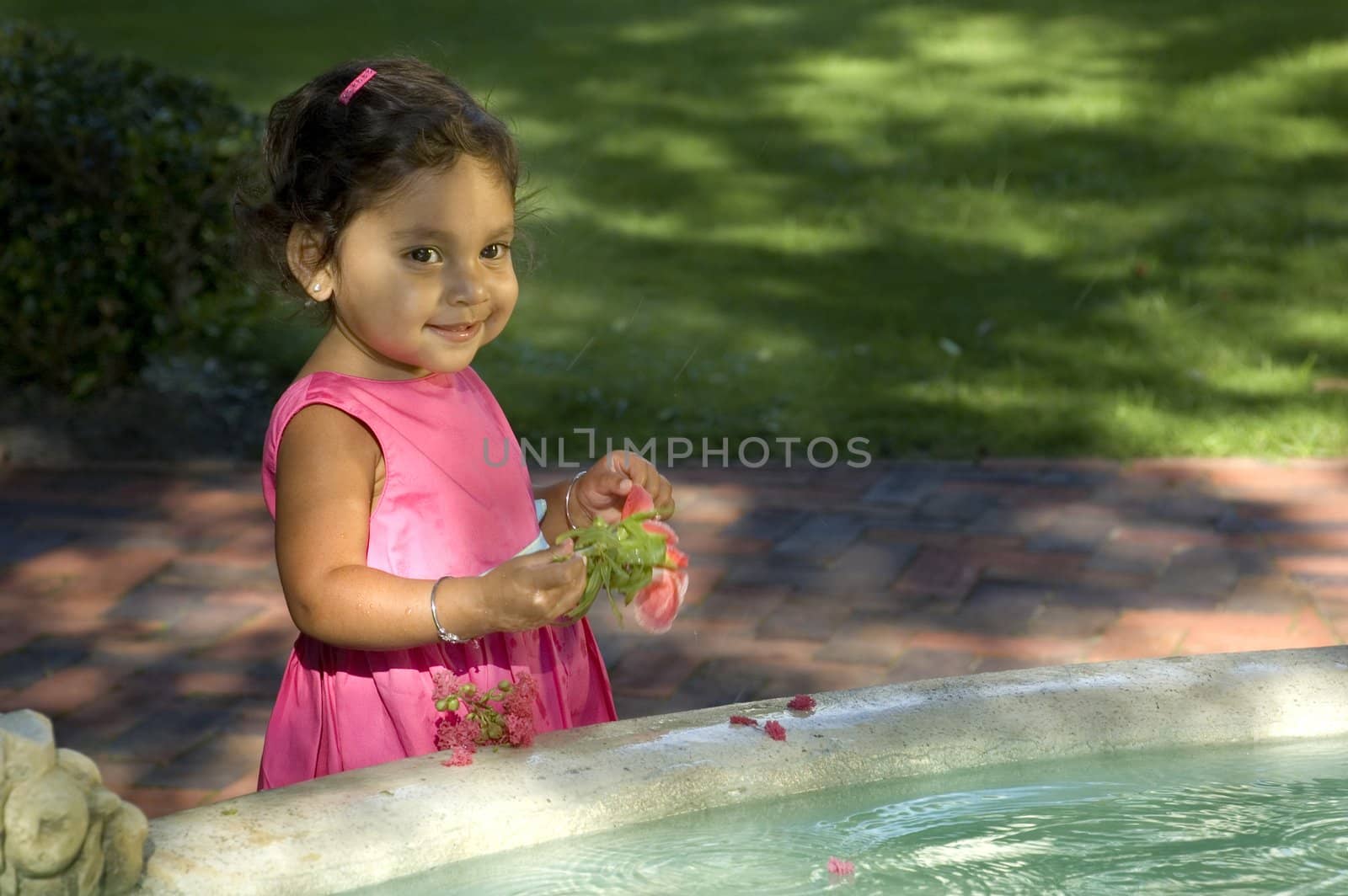 A little Indian girl plays in a fountain.