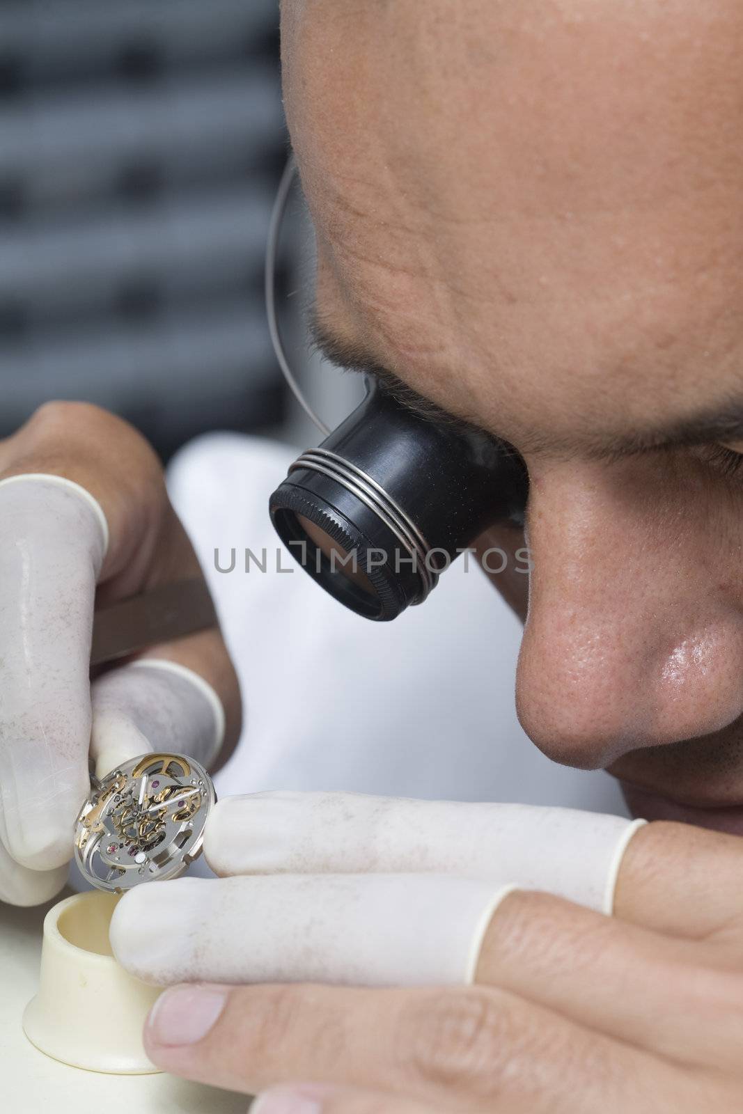 A watchmaker or repair man in action, viewing very closely a swiss watch.
