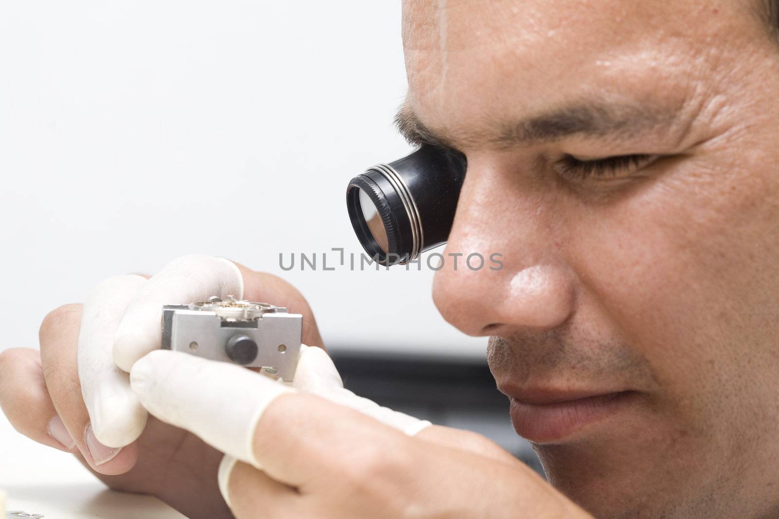 A watchmaker or repair man in action, viewing very closely a swiss watch.