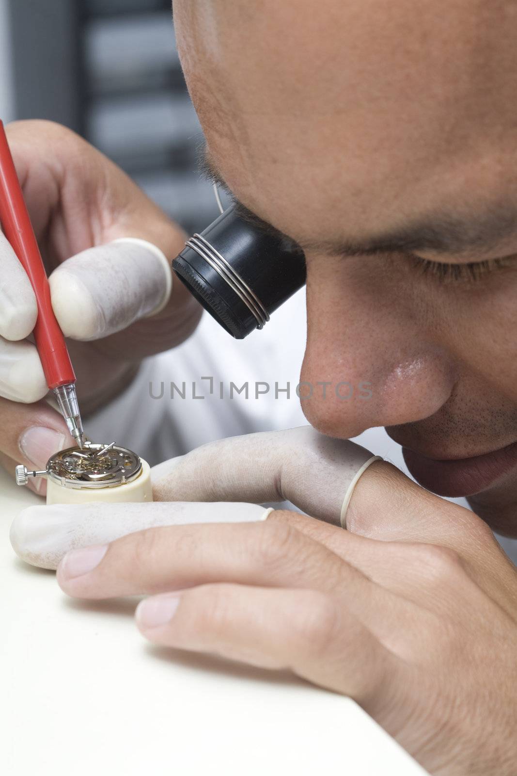 A watchmaker or repair man in action, viewing very closely a swiss watch.