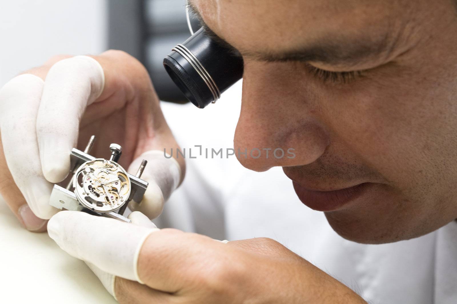 A watchmaker or repair man in action, viewing very closely a swiss watch.