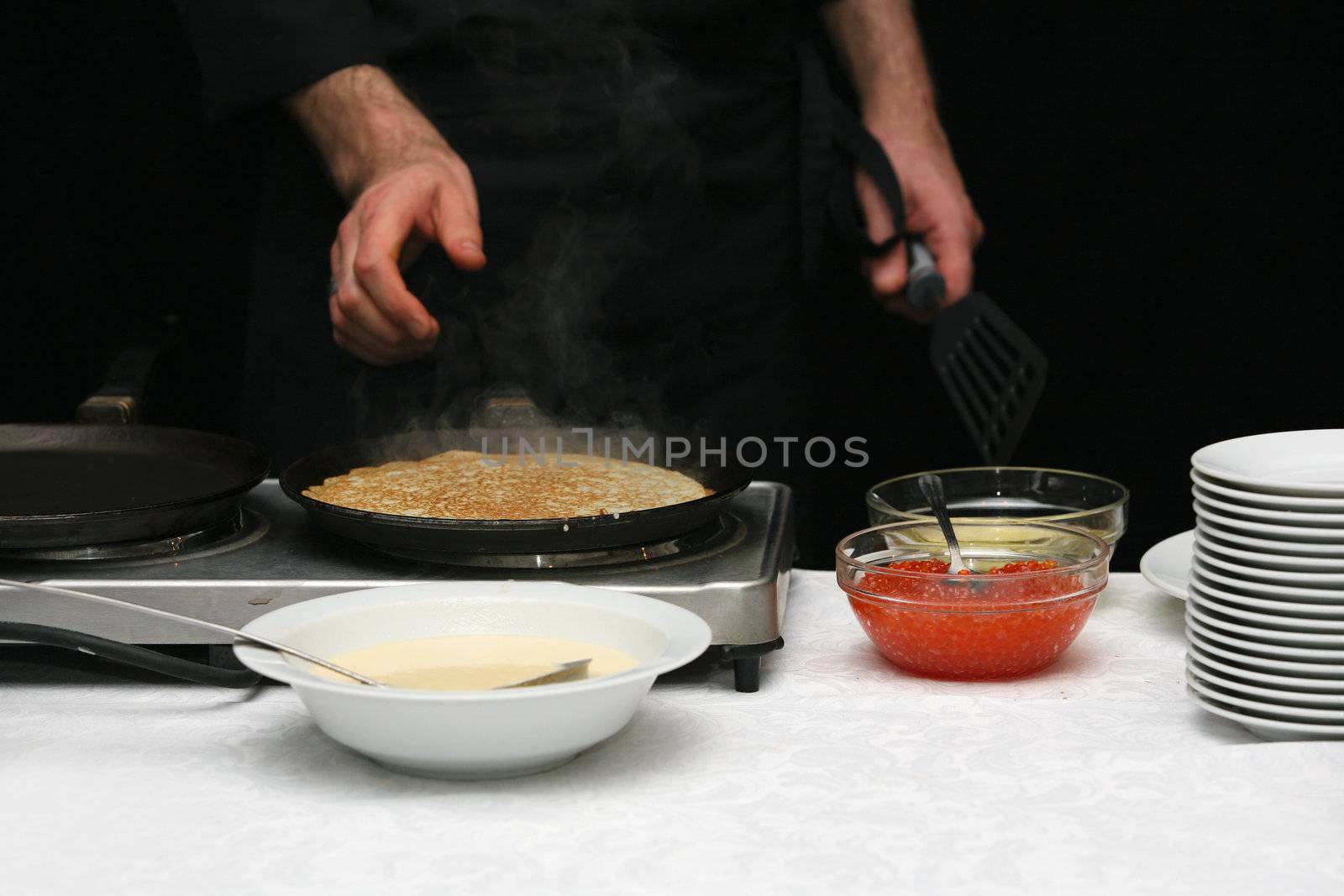 The cook fries pancakes with caviar
