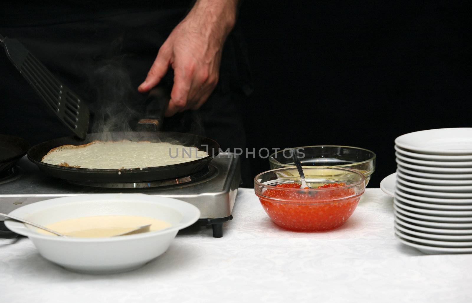 The cook fries pancakes with caviar