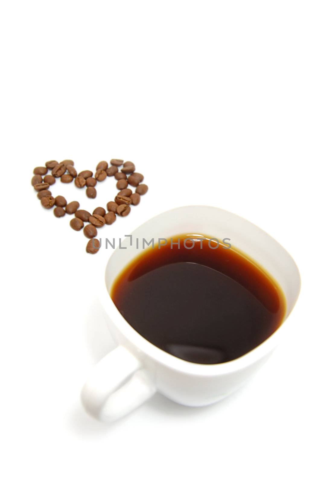 cup of coffe and coffee beans in heart shape on white