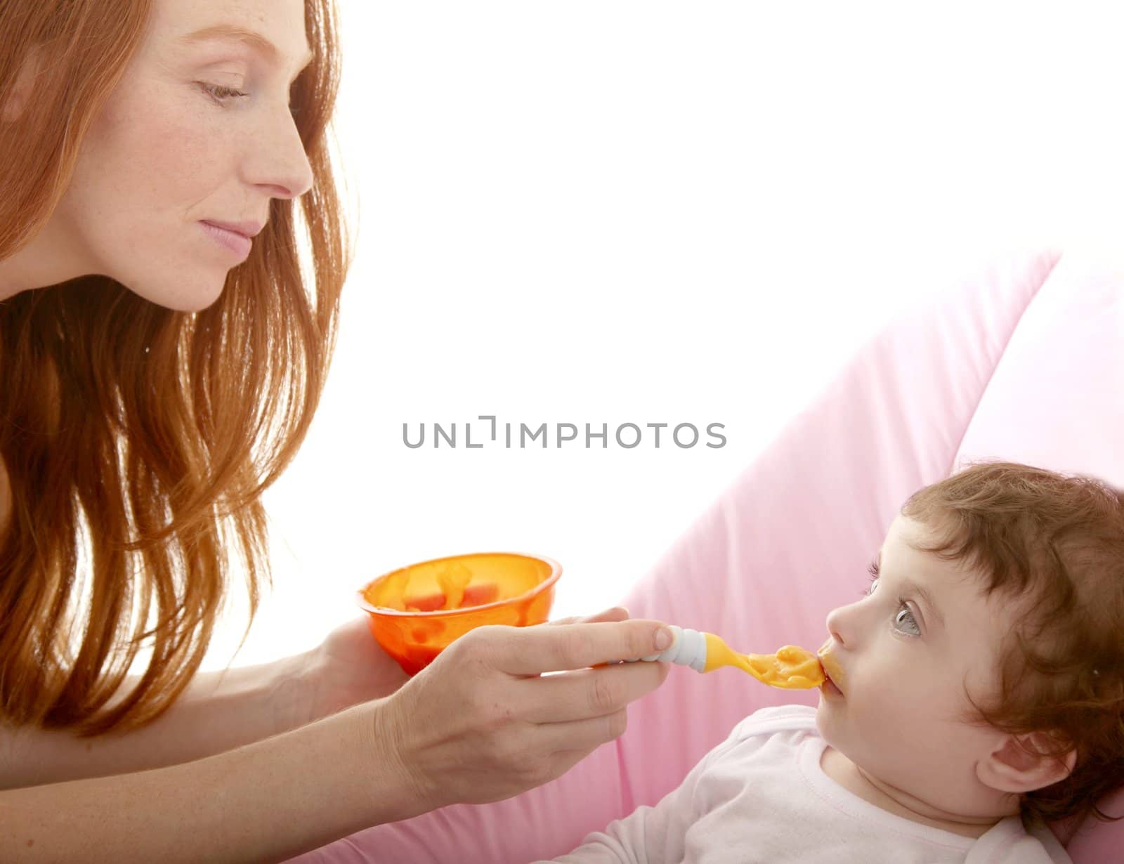 mother feeding baby yellow spoon white background