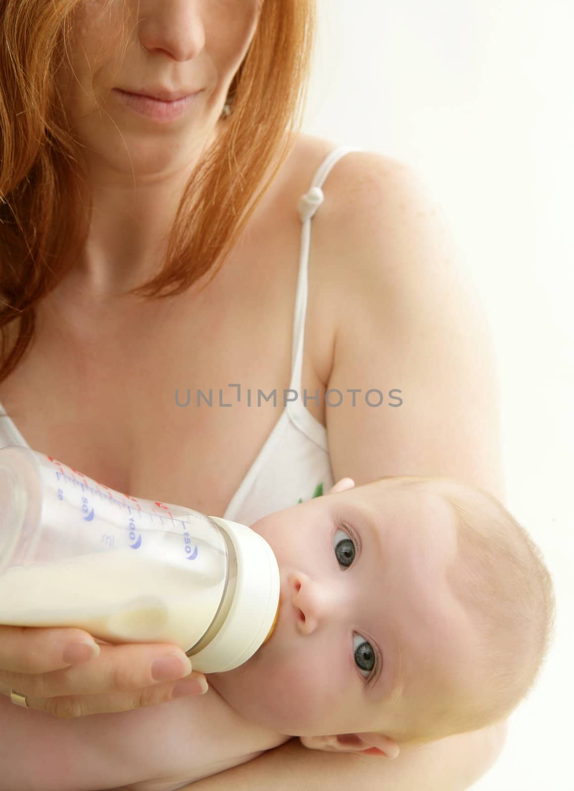 baby blond drinking bottle from mother hands