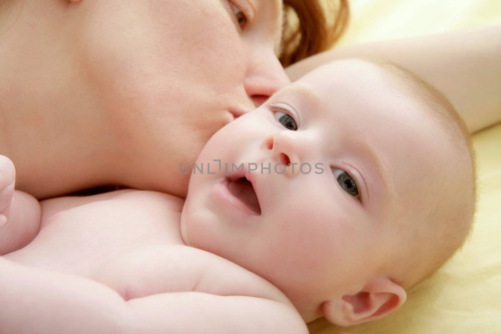 mother kissing little baby smiling on white background