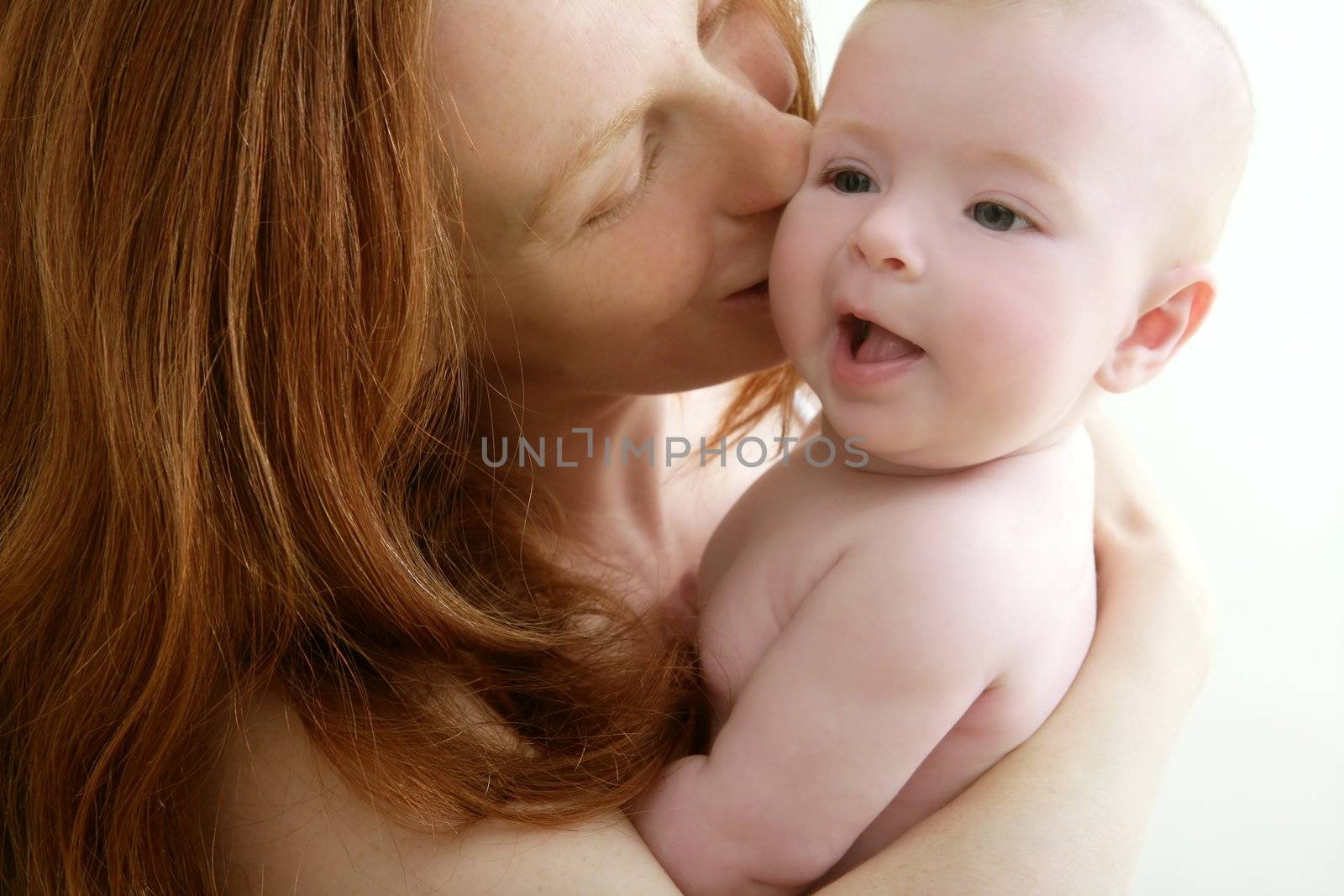 mother kissing little baby smiling on white background