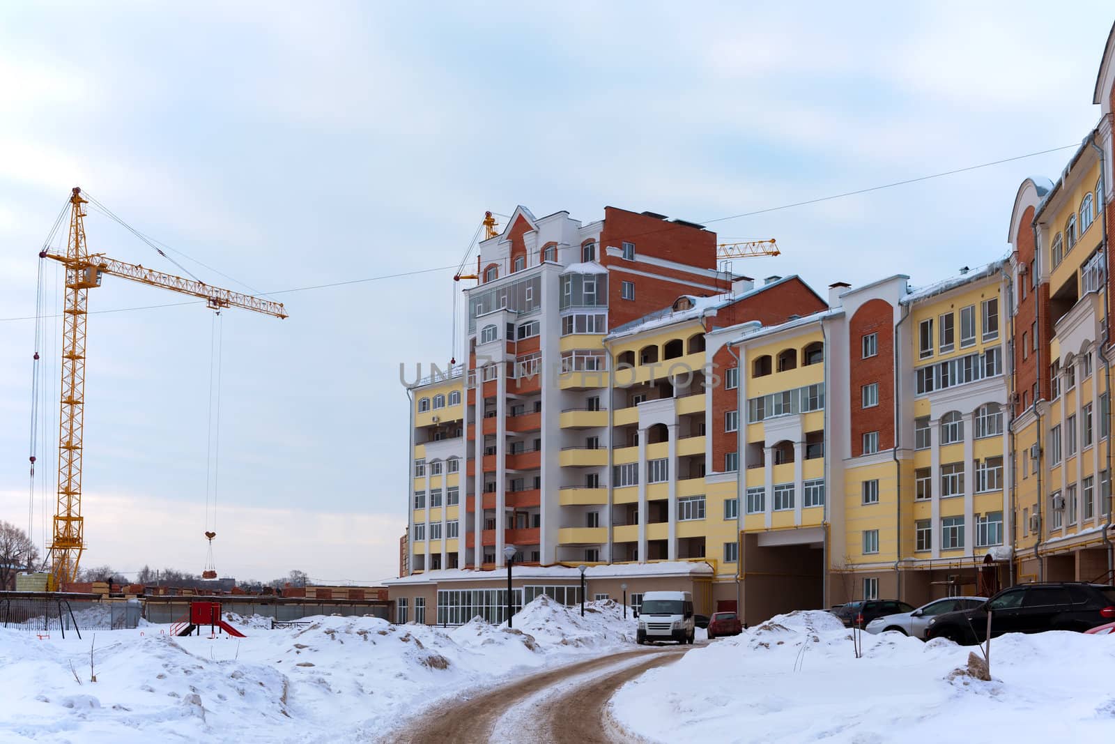 Building crane and building under construction against the white snow

