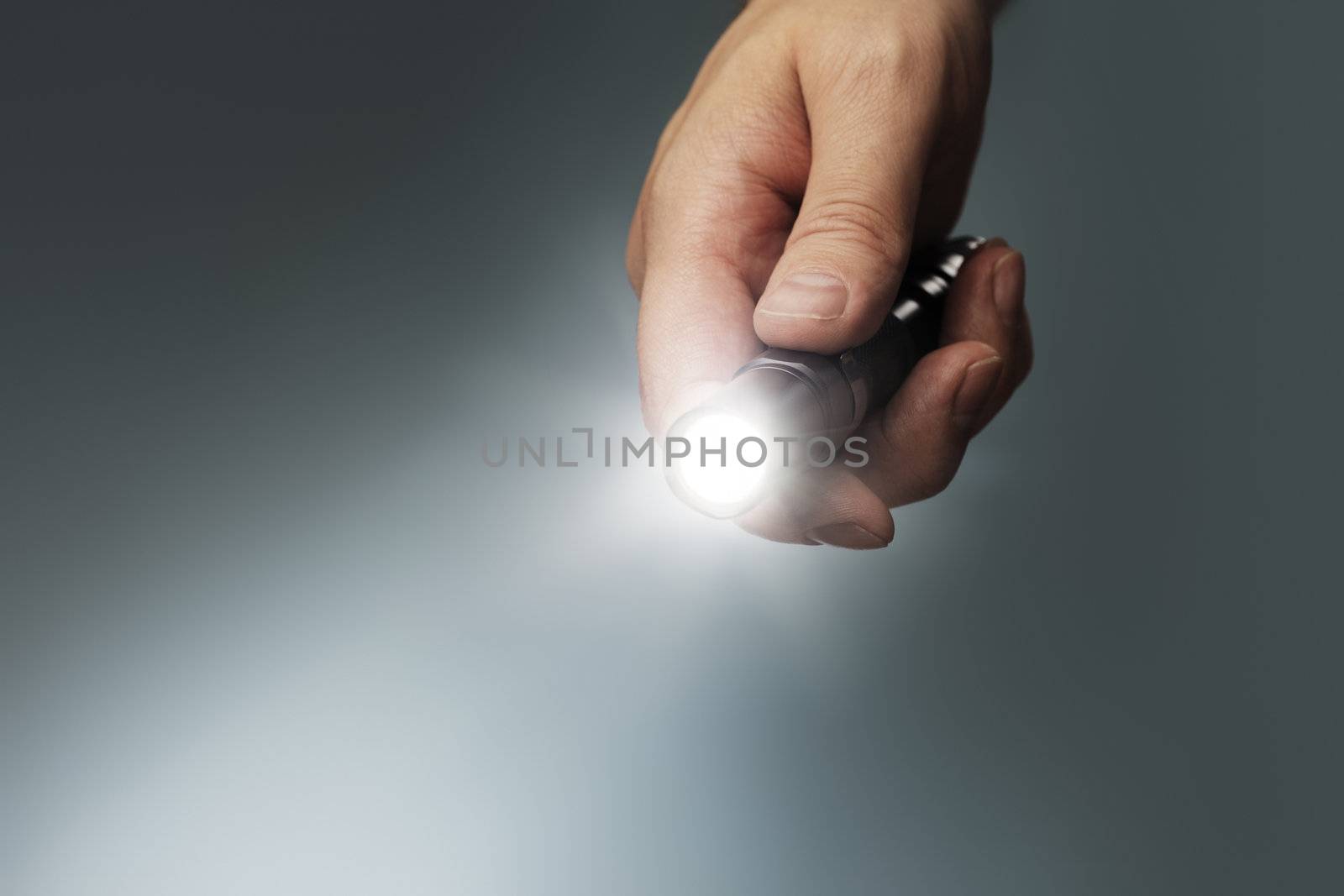 Man holding a small but powerful led flashlight in his hand.