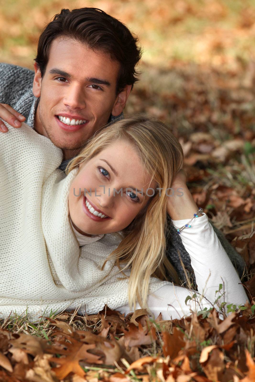 Couple laying in pile of brown leaves