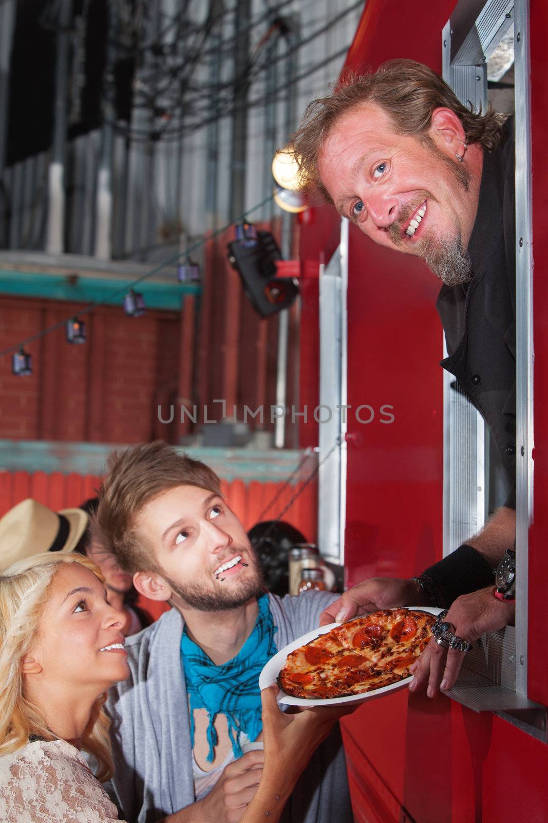 Smiling Chef holding pizza with teenage couple