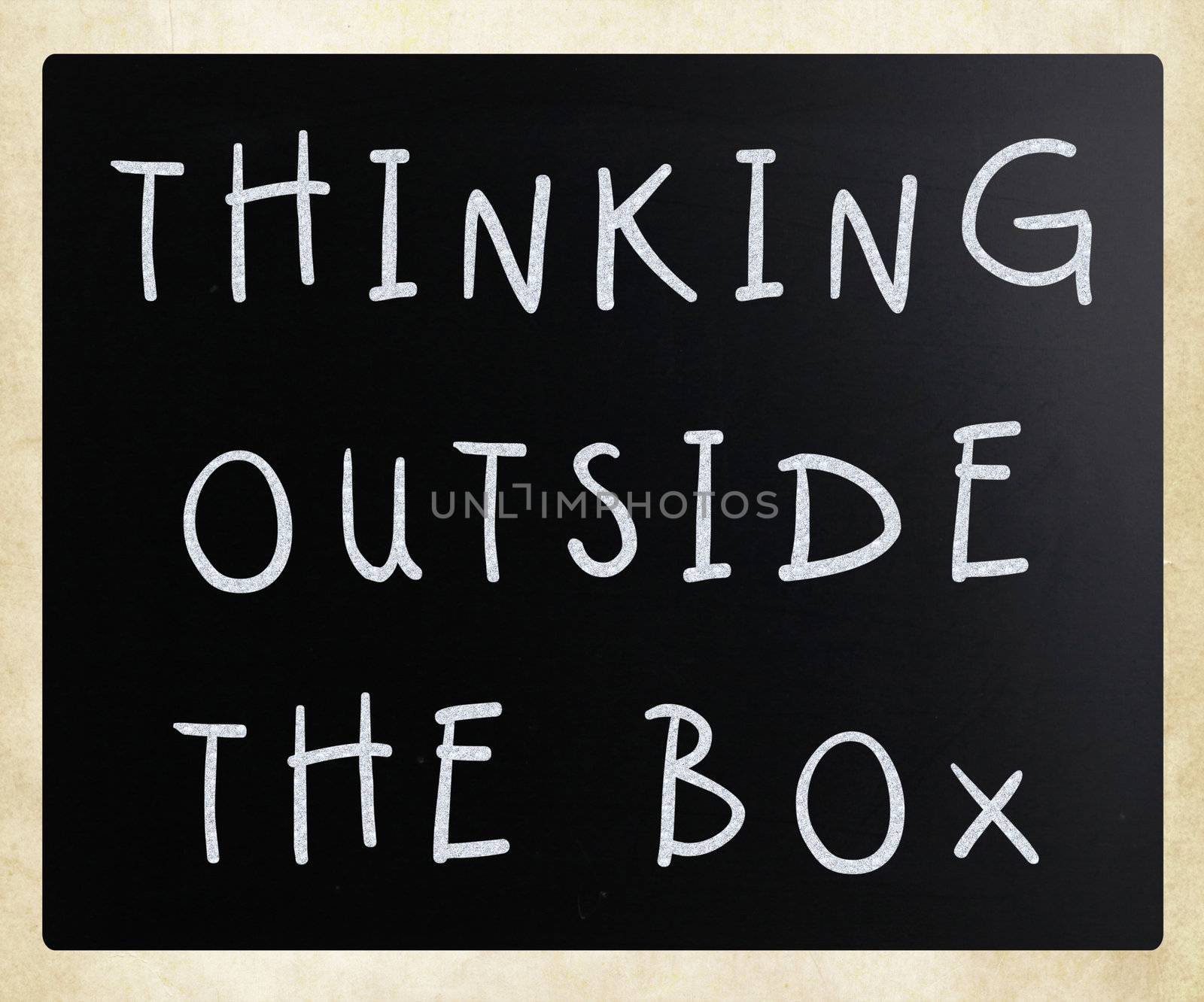 Thinking outside the box phrase, handwritten with white chalk on a blackboard
