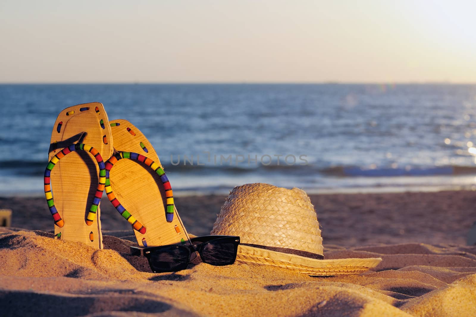 Wicker hat, sandaland glasses on the sandy beach