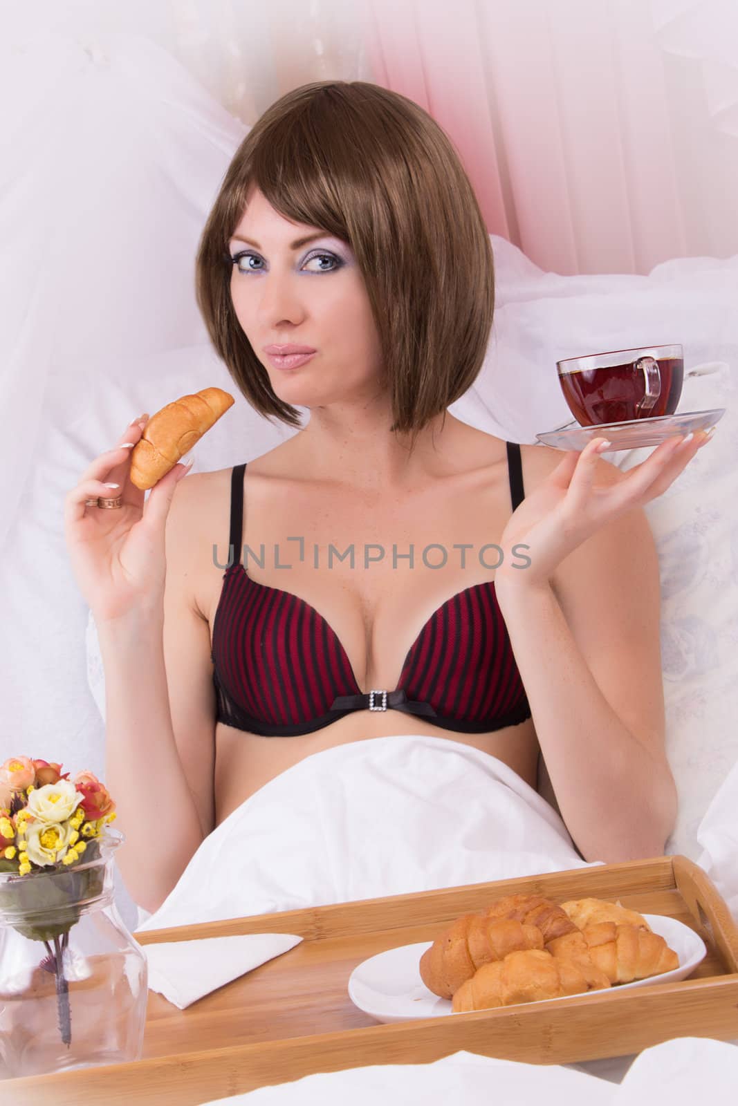 Brunette sensual woman in lingerie with cup of tea in bed