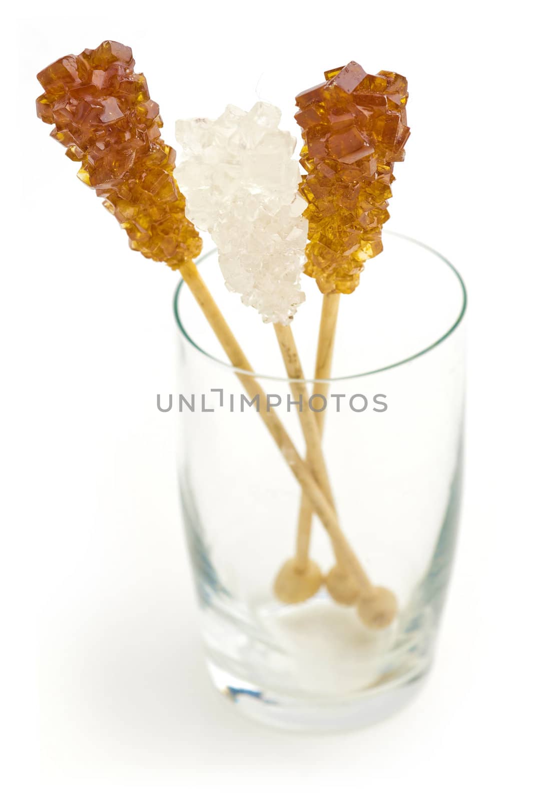 Candy brown and white sugar on a sticks in glass. Soft focus. With white background.