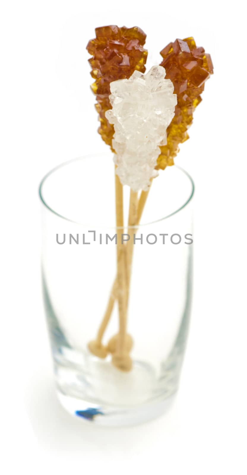 Candy brown and white sugar on a sticks in glass. Soft focus. With white background.