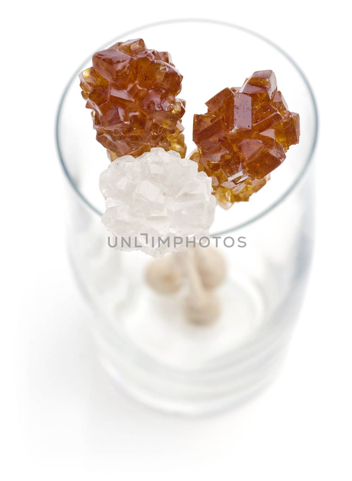 Candy brown and white sugar on a sticks in glass. Soft focus. With white background.