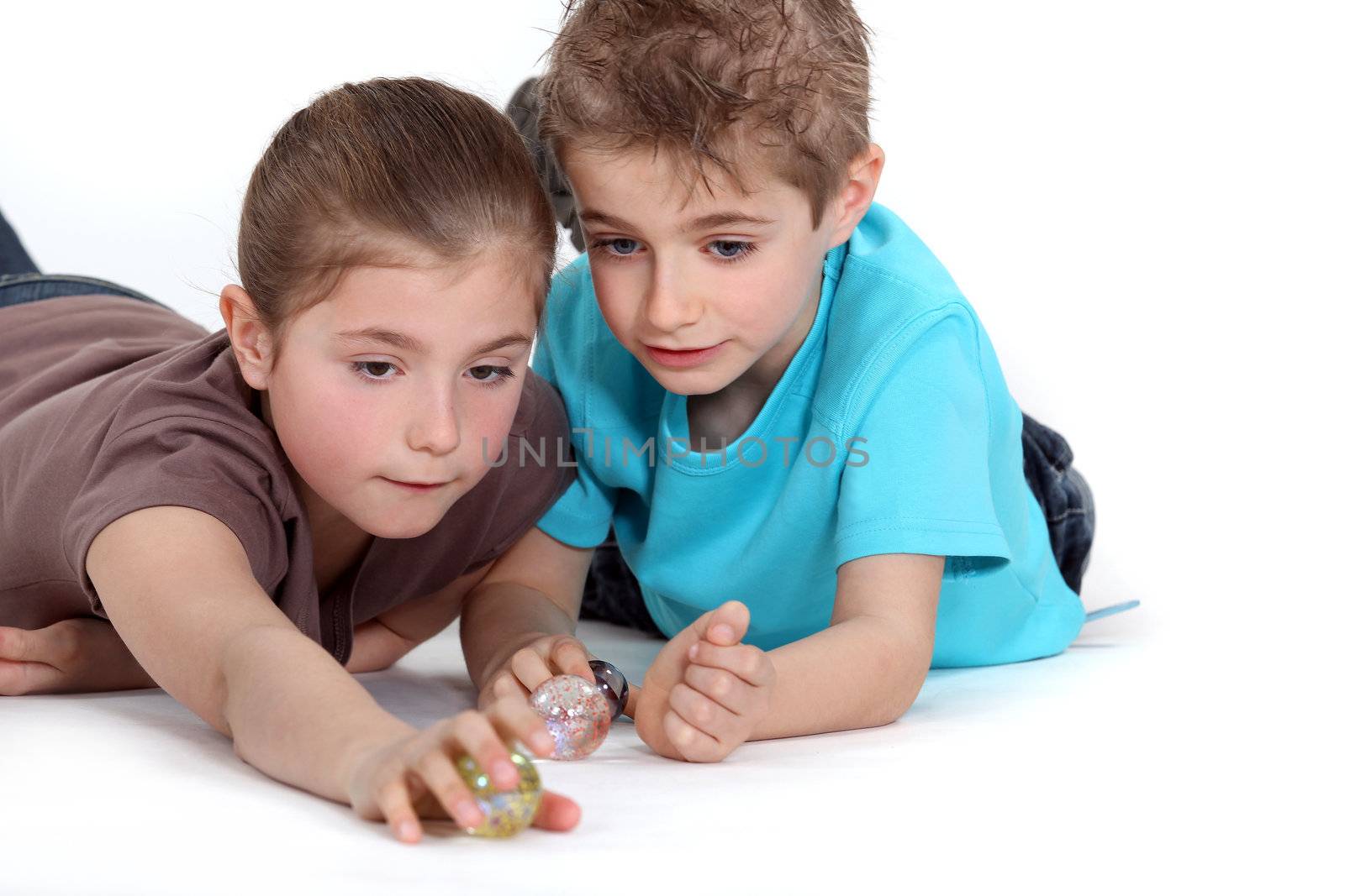 Brother and sister playing with marbles by phovoir