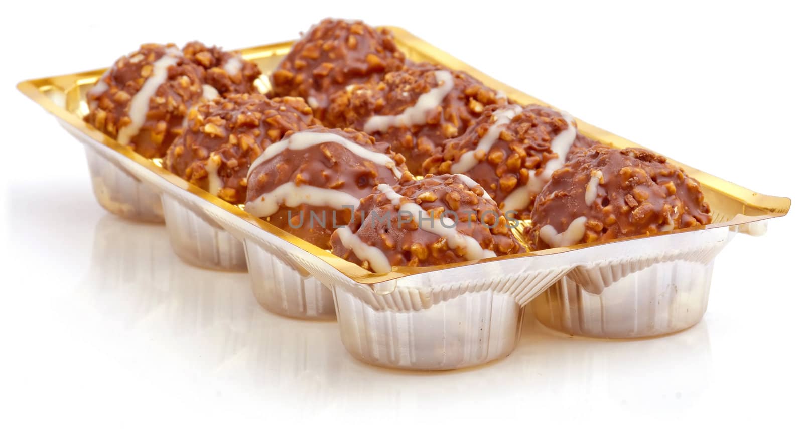 Sweet chocolate balls filled with hazelnuts in plastic package on a white background.