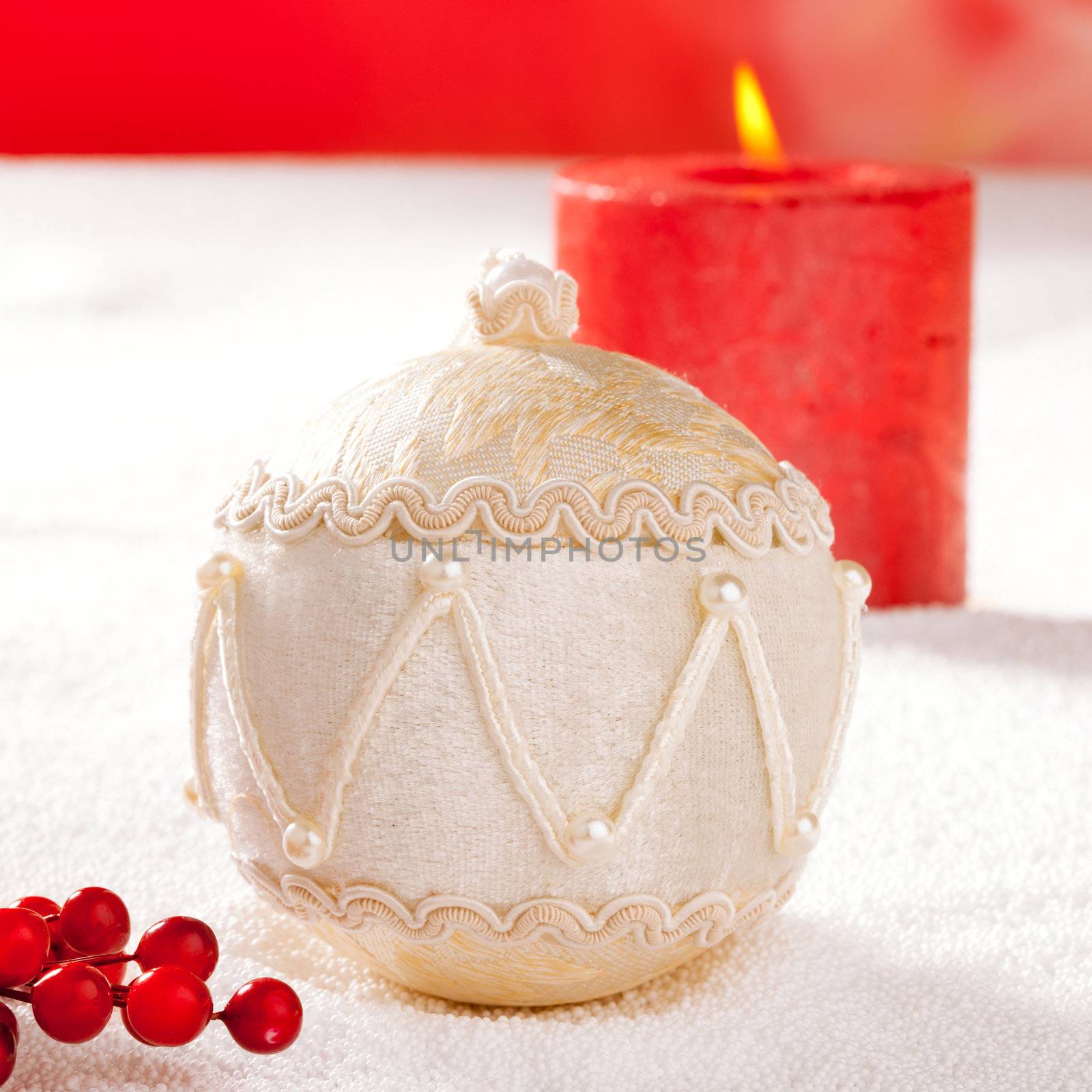 Christmas card of white velvet bauble and red candle on snow background