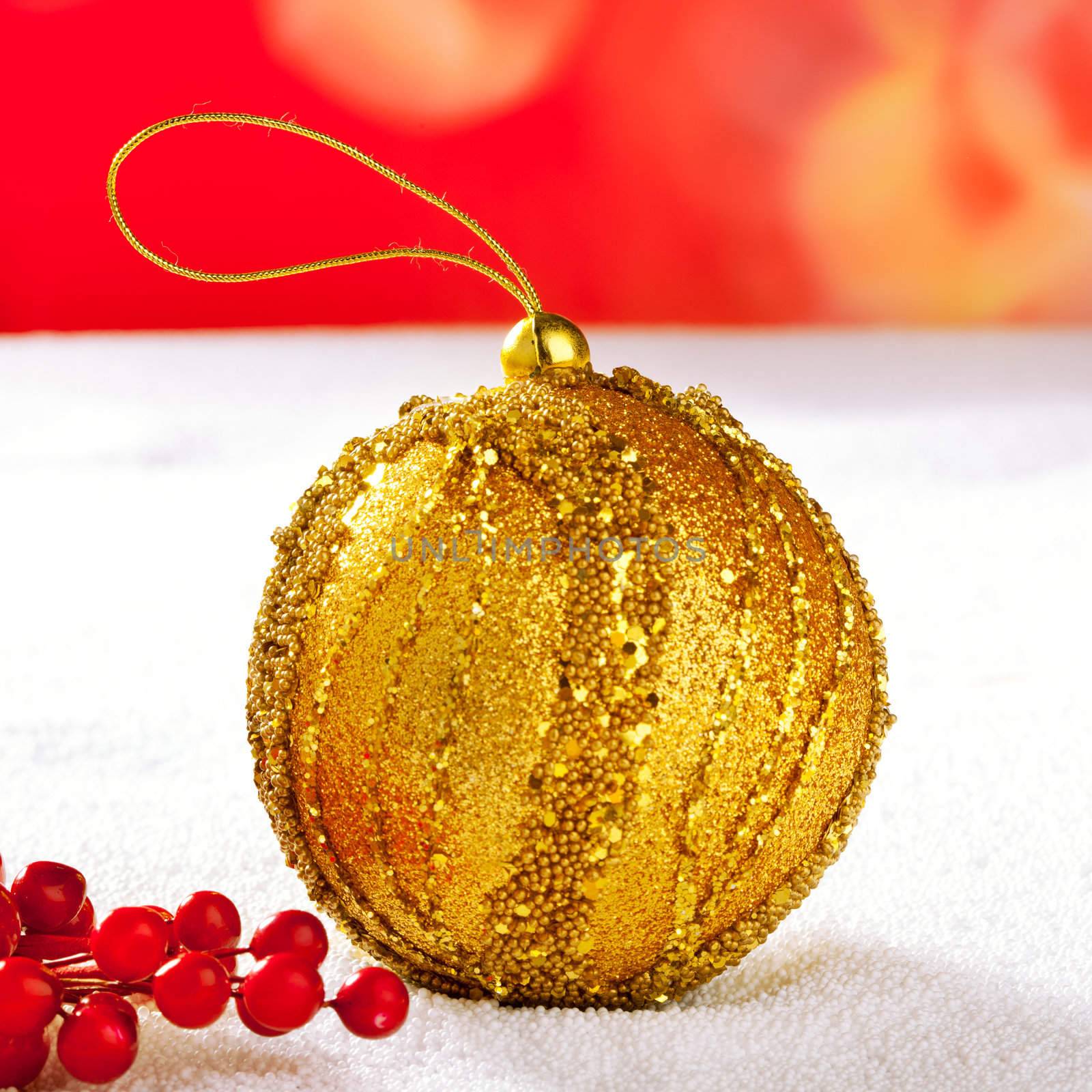 Christmas card of golden bauble berries on snow and red background