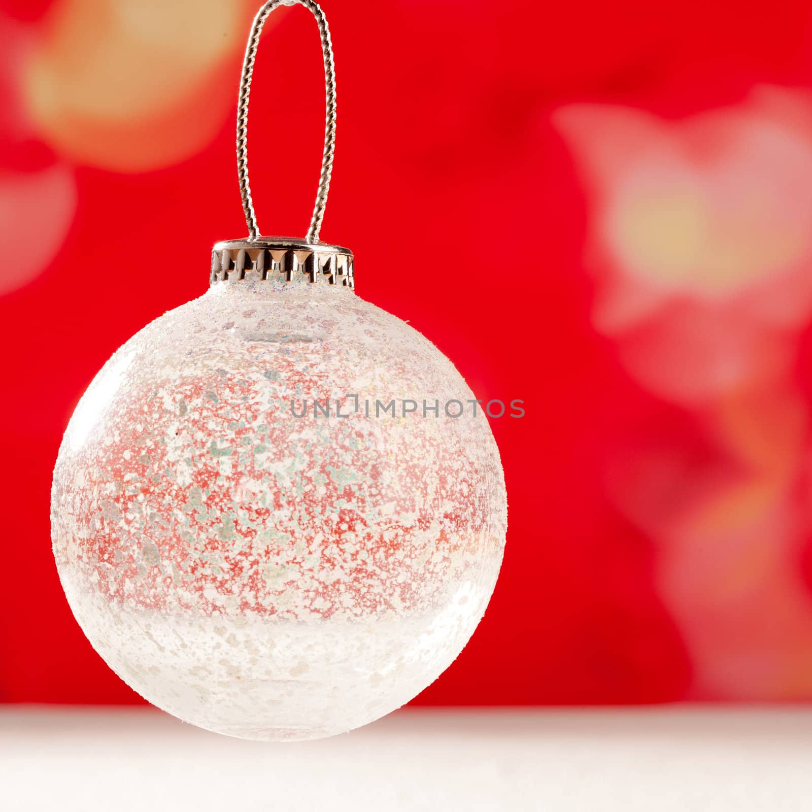 Christmas glass transparent bauble on snow and red background