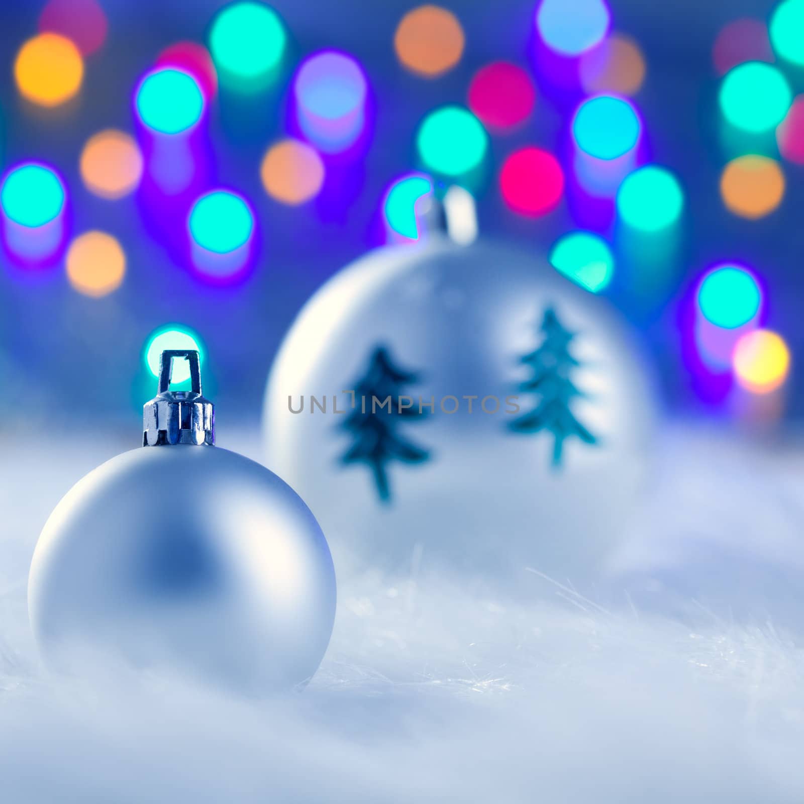 christmas silver baubles witn tree and burred lights background