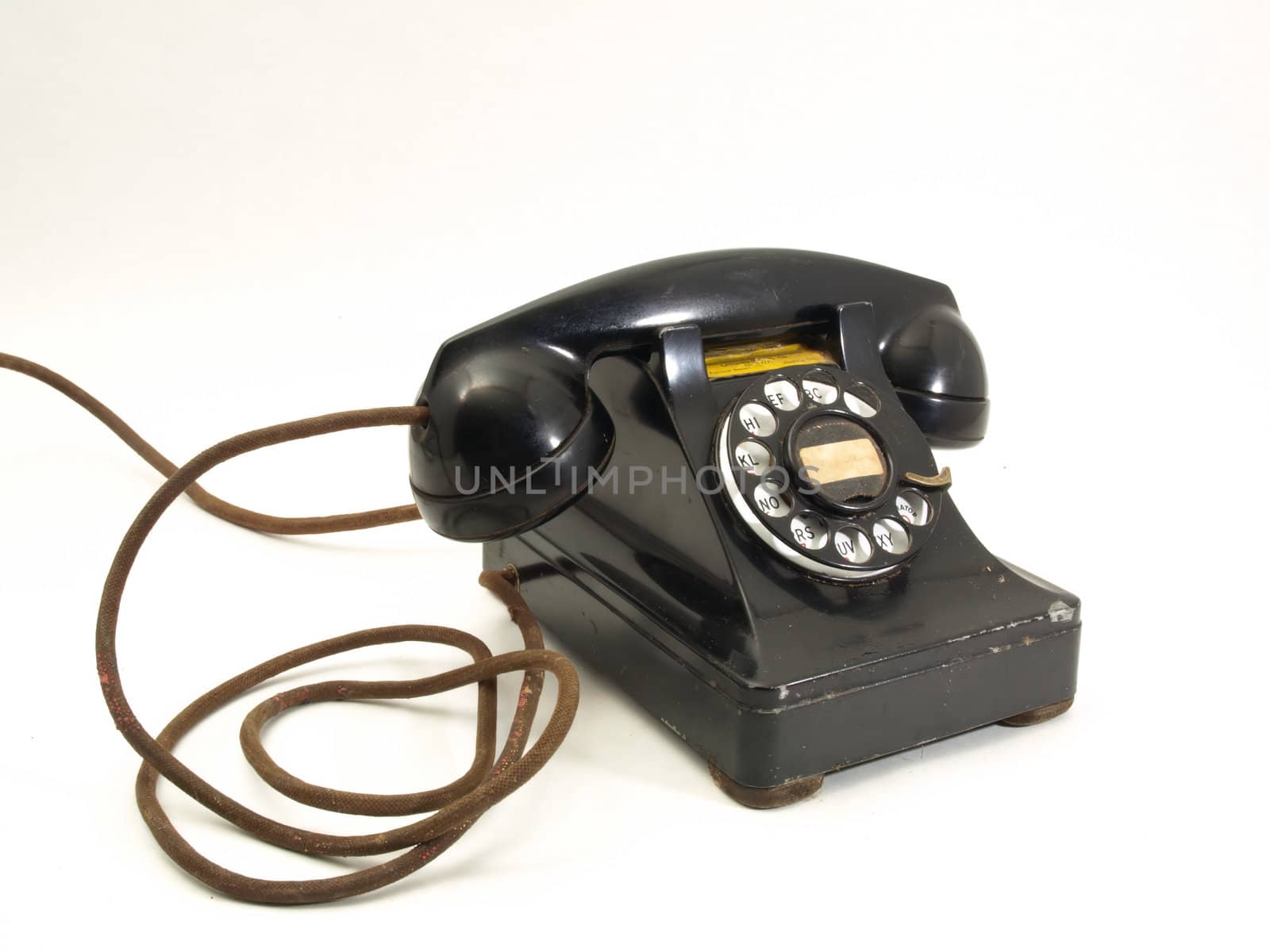 An antique black rotary dial telephone isolated against a white background.