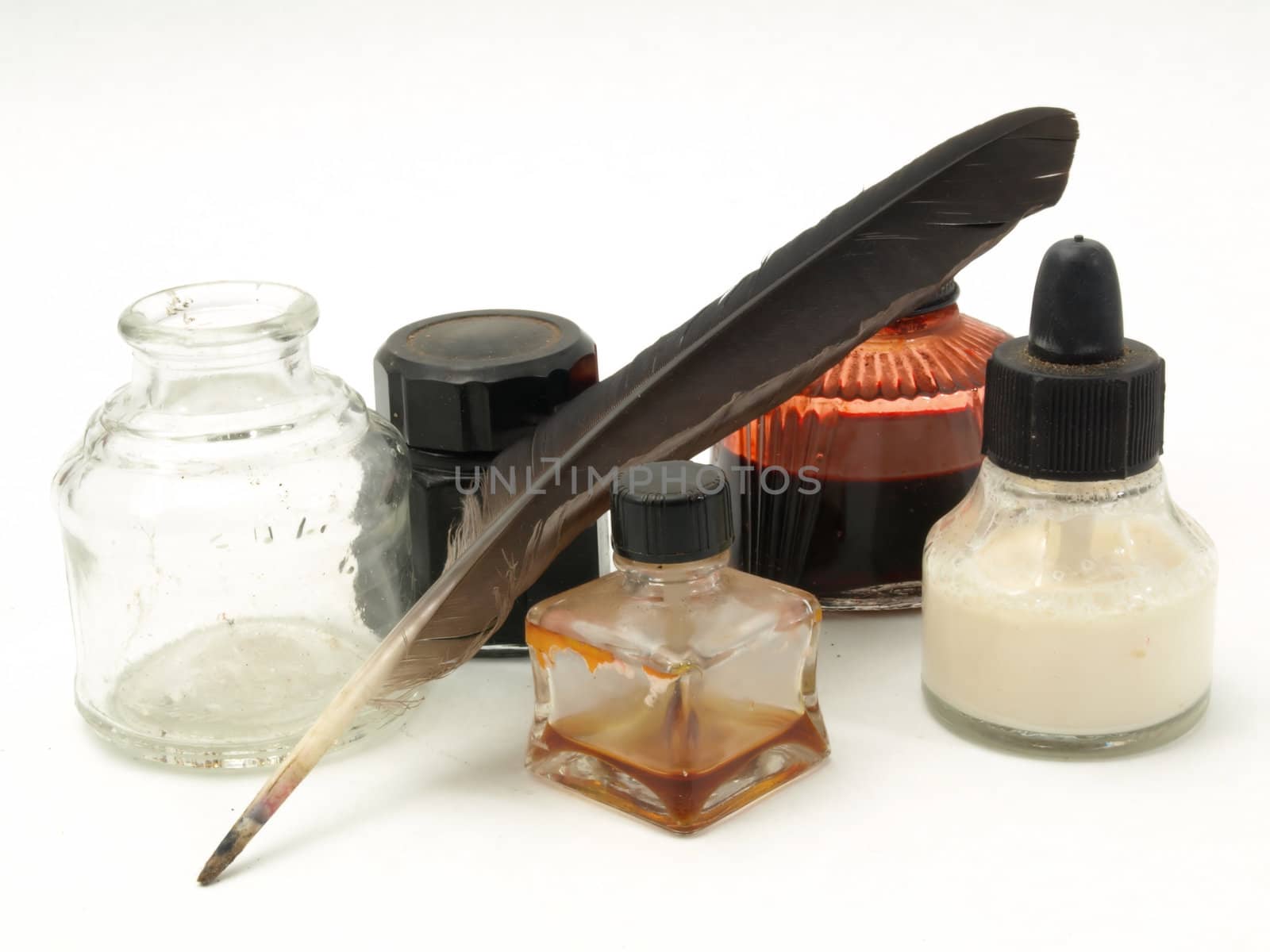 Several old glass ink bottles and a well with brown quill. Isolated over white.