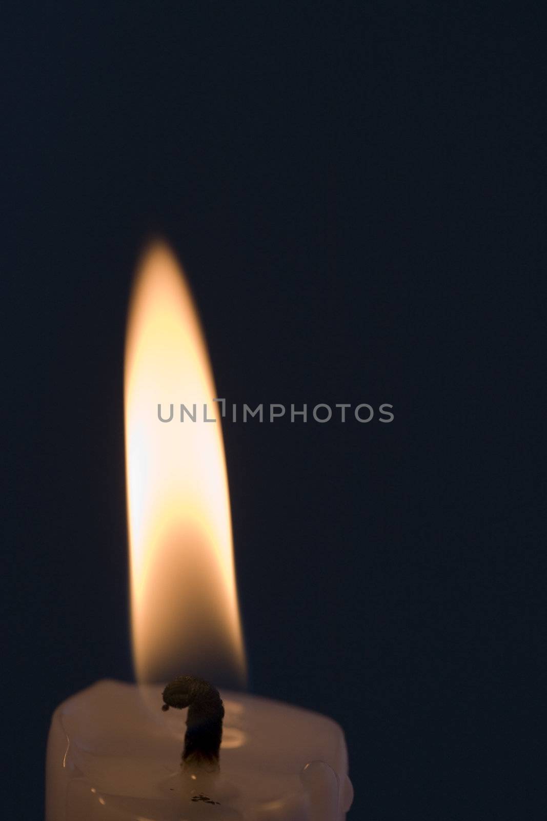 A single candle flame with a black background
