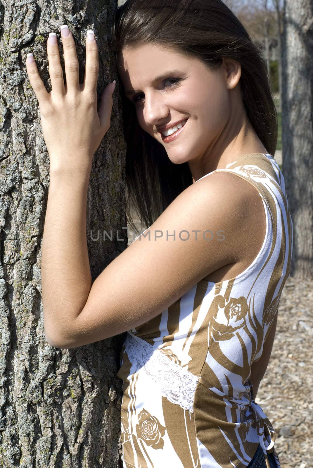 A beautiful and cute model outside stading next to a tree.