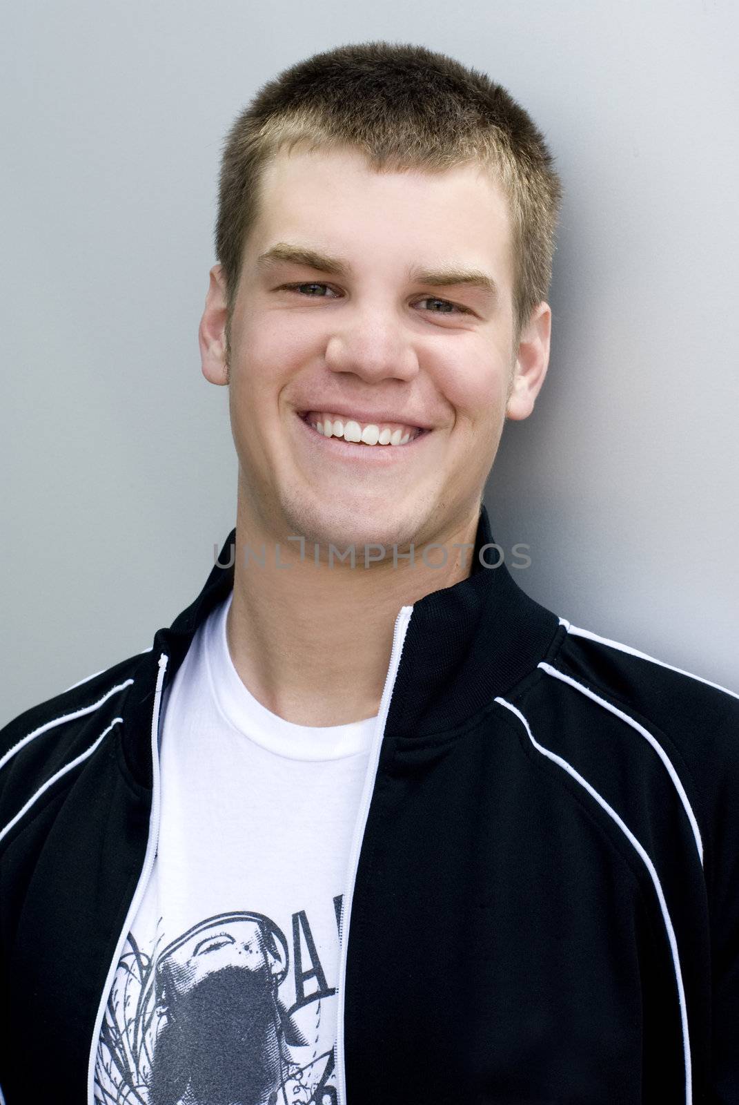 A young man outside against a wall.