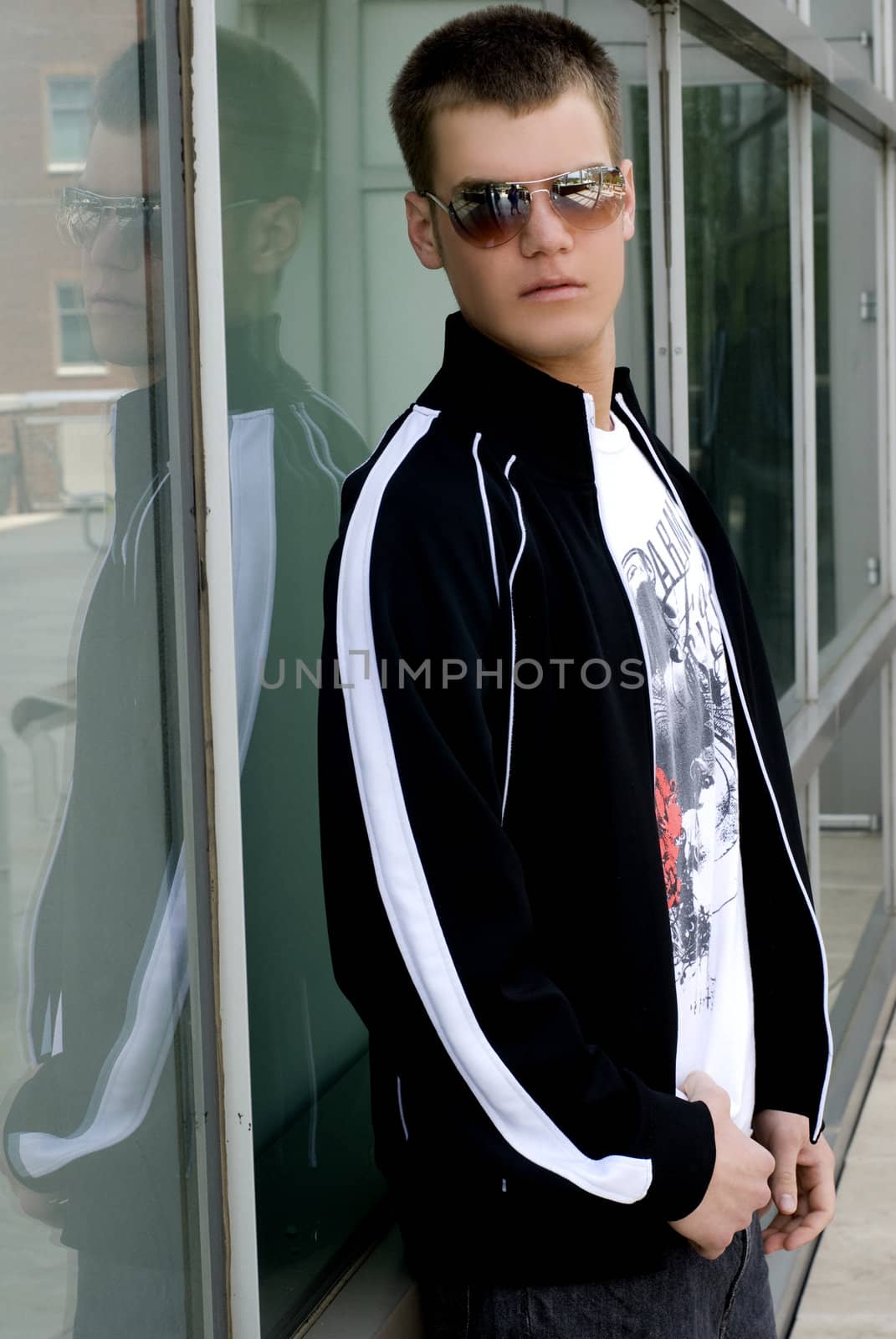 A young man outside against a wall.