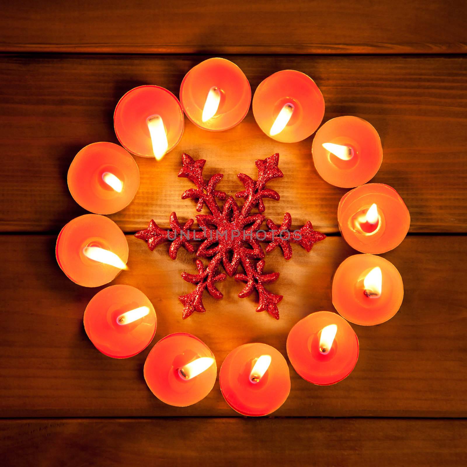 christmas candles circle over wood and red snowflake symbol