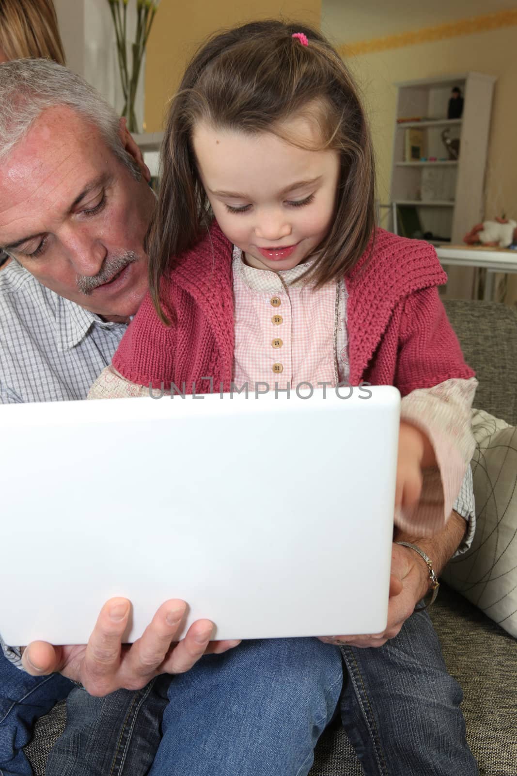 Grandfather with granddaughter and computer by phovoir