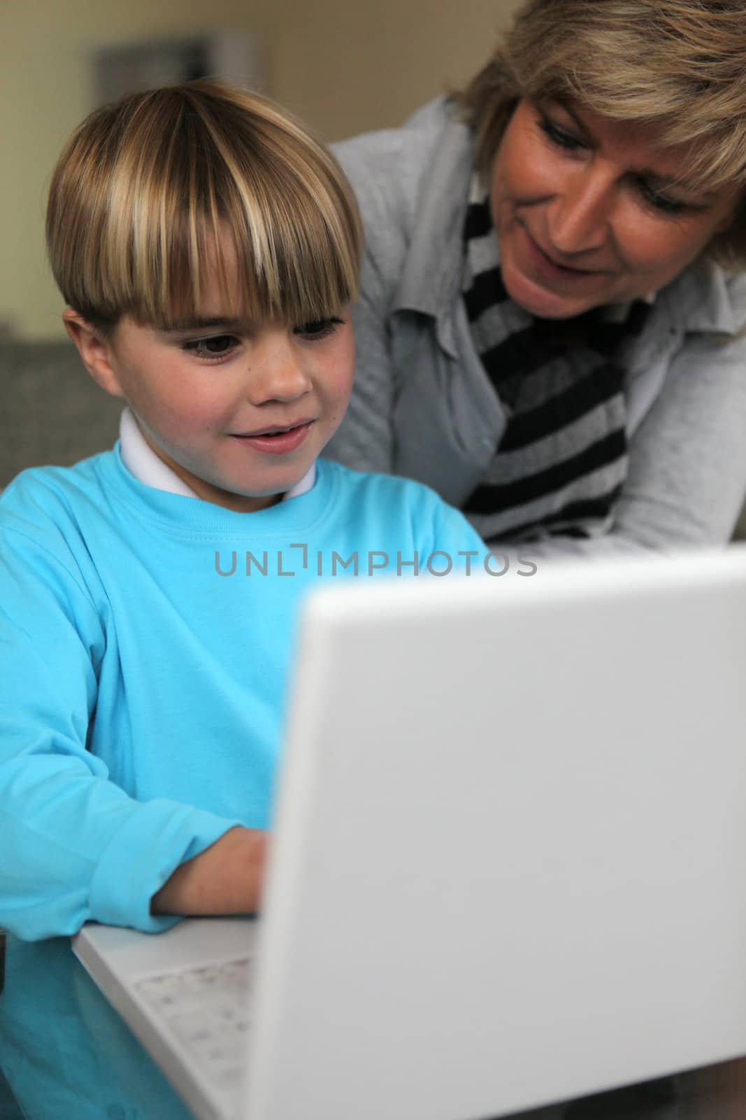 Mother and son using laptop together on sofa