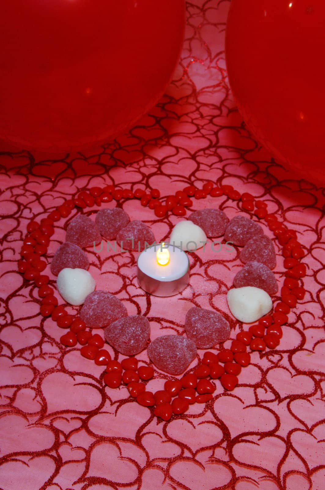 A background of material with hearts and cinnamon candies and balloons